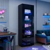 A modern gaming room setup with a black high-gloss display cabinet filled with items and illuminated by blue LED lights, next to a desk with a computer and headphones, and a blue sofa in the background. Anteprima dell’immagine prodotto