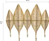 A gold-colored wall-mounted coat rack shaped like five stylized feathers, each with a hook at the bottom. Produktbild-Vorschau