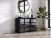 A modern living room with a black dresser, a round mirror, and a large potted plant. Voir les images du produit