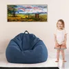 A child stands next to a large blue beanbag chair in a room with a painting on the wall. Voir les images du produit