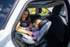A woman is putting a baby into a car seat inside a car. Podgląd zdjęcia produktu