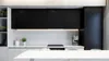 A modern kitchen with black cabinets, white countertops, and a marble island in the foreground. Produktbild-Vorschau