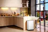 A modern kitchen with wooden cabinets, a stainless steel trash can, and a large window overlooking a city. Voir les images du produit