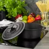 A cast iron pot and lid are placed on a black induction stovetop, with fresh vegetables and pasta in the background. Produktbild-Vorschau