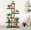 A multi-tiered wooden plant stand filled with various potted plants, set against a white wall. Produktbild-Vorschau
