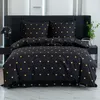 A neatly made bed with black bedding featuring a pattern of golden hearts. Produktbild-Vorschau