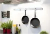 A kitchen scene with pots hanging on a rack, spice rack, and plants. Podgląd zdjęcia produktu