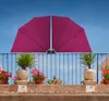 A balcony railing with potted plants and a pink umbrella attached to the railing. Produktbild-Vorschau
