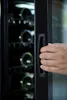 A person's hand opening a wine cooler. Produktbild-Vorschau