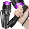 A hand holding a black LED flashlight with a purple light emitting from the front. Another flashlight is visible in the background. Produktbild-Vorschau