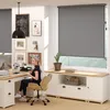 A woman is working at a desk in a home office with a large window covered by a roller blind. Produktbild-Vorschau