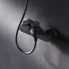 A black shower faucet mounted on a dark gray textured wall. Produktbild-Vorschau