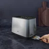 A toaster on a kitchen counter with a hand pulling out the crumb tray. Náhľad obrázku produktu