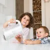Two children are in a kitchen, with an older girl pouring water from a pitcher into a glass for a younger child. Podgląd zdjęcia produktu