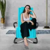 A woman is sitting on a blue lounge chair in a modern living room setting. Produktbild-Vorschau