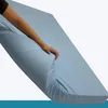 A hand is shown pressing down on a light blue mattress, demonstrating its flexibility and softness. Produktbild-Vorschau