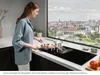 A woman is cooking on an induction hob with a view of a city skyline. Anteprima dell’immagine prodotto