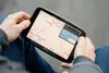 A person is holding a GPS navigation device with a map displayed on the screen. Voir les images du produit