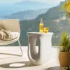 A modern white side table with a bottle and glass on it, placed on a balcony with a scenic view of hills and the sea. Náhled obrázku produktu