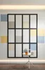 A modern interior scene featuring a large, grid-like wall decoration with colored panels and a small side table with decorative items. Produktbild-Vorschau