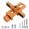 A close-up, angled view of an orange metal jig for drilling holes, with various accessories shown below. Produktbild-Vorschau