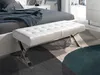 A white bench in front of a bed in a bedroom. Náhled obrázku produktu