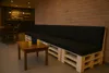 A lounge area with a pallet sofa and a small wooden table with two glasses of orange juice. Produktbild-Vorschau