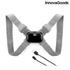 A posture corrector device with straps and a central electronic unit, along with charging cables, is displayed against a white background. Podgląd zdjęcia produktu