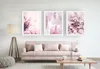 A living room scene with a pink sofa, a coffee table, a floor lamp, and three framed floral art prints on the wall. Náhľad obrázku produktu