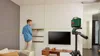 A man is installing shelves on a wall, using a laser level to ensure they are straight. A TV and media console are visible in the room. Anteprima dell’immagine prodotto