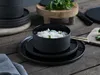 A table setting with black stoneware dishes and a bowl of noodles. Náhľad obrázku produktu