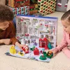 Two children are playing with a Paw Patrol advent calendar and toys on a rug, with Christmas gifts in the background. Podgląd zdjęcia produktu