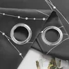 Close-up of two grommets on a dark gray curtain with a white line and dot pattern. Produktbild-Vorschau