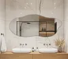 A modern bathroom with two sinks and a large, irregularly shaped mirror. Produktbild-Vorschau