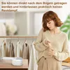 A woman is standing next to a rack of clothes while holding a small white handheld garment steamer. Produktbild-Vorschau