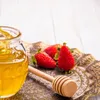 A close-up shot of a jar of honey with a honey dipper and strawberries on a decorative tray. Podgląd zdjęcia produktu