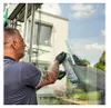 A man is cleaning a large window with a squeegee and a scrubber. Produktbild-Vorschau