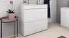 A white shoe cabinet with two drawers is shown in a hallway setting next to a small side table with a potted plant. Produktbild-Vorschau