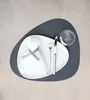 A place setting with a plate, napkin, cutlery, and a glass on a dark gray placemat. Produktbild-Vorschau