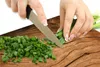 Hands chopping green onions on a wooden cutting board. Produktbild-Vorschau