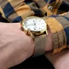 A close-up shot of a person's wrist wearing a gold Tommy Hilfiger watch. Voir les images du produit