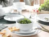 A table setting with white plates, a bowl of salad, and crackers. Produktbild-Vorschau