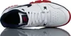 A top-down view of a white Nike cross-trainer shoe with navy and red accents, resting on a reflective surface. Náhled obrázku produktu