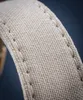 A close-up of a beige fabric watch strap with visible stitching. Voir les images du produit