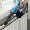 A person is vacuuming a radiator with a handheld vacuum cleaner. Produktbild-Vorschau