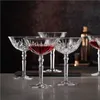 A set of crystal cocktail glasses filled with red liquid, arranged on a surface with a dark, textured background. Produktbild-Vorschau