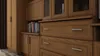 A close-up view of wooden furniture with drawers and cabinets. Produktbild-Vorschau