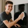 A young man is cleaning a TV screen with a white cloth. Produktbild-Vorschau