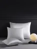 Three white silk pillowcases are arranged on a gray surface in front of a dark gray wall. Podgląd zdjęcia produktu