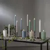 A collection of LED candles of various colors and sizes are arranged on a rustic wooden table, decorated with ivy. Produktbild-Vorschau